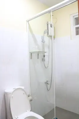 a white bathroom with a shower with a toilet at Anicia Guesthouse Units in Manila