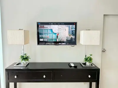 a tv on a wall with a table with two lamps at Spacious BGC 2 BR with a view in Manila
