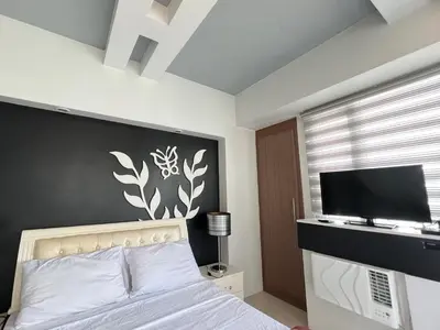 a bedroom with a bed and a flat screen tv at Condotel Across Naia Airport with WIFI in Manila