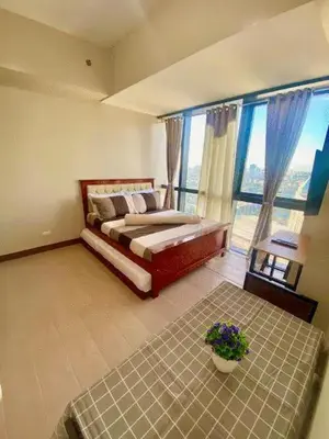 a bedroom with a bed and a large window at AFFORDABLE StayCation EASTWOOD CITY in Manila