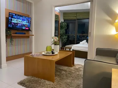 a living room with a couch and a table and a tv at Lux Skyline KL Greenbelt, Isabel's Makati Rooms in Manila