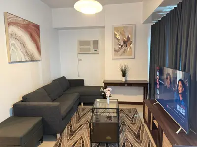 a living room with a couch and a tv at 1 Bedroom Bayview Condo near SLMEC & US Embassy in Manila