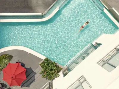 a person swimming in a swimming pool with a red umbrella at Luxxe interior design condo - Residences at Acqua private residences in Manila