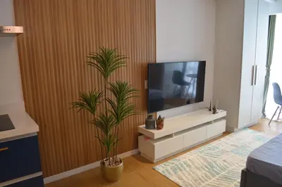 a living room with a television and two plants at Luxxe interior design condo - Residences at Acqua private residences in Manila