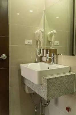 a bathroom with a white sink and a mirror at StayHere Skandanavian Designed 1BR in Greenbelt in Manila