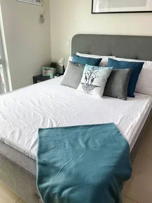 a bed with blue and white pillows on it at Modern and homely Condo in Shaw Boulevard in Manila