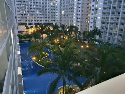 a view of a swimming pool in a city at night at Home at Last, 1 Bedroom Pool View with Balcony in Manila