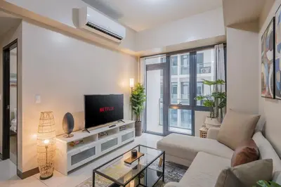 a living room with a couch and a tv at StayHere The Florence Luxe 1BR Near Venice Mall in Manila