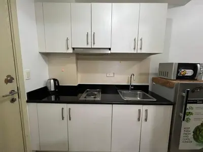 a small kitchen with white cabinets and a sink at Jazz Residences Makati in Manila