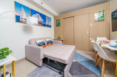 a dining room with a table and a chair at 2 Side-by-Side P00L Front Condos, 6 Beds, 2 CR, 2 Kitchen at MOA in Manila