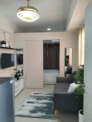 a living room with a couch and a tv at Cozy 2BR corner unit in a prime location, your perfect city home in Manila