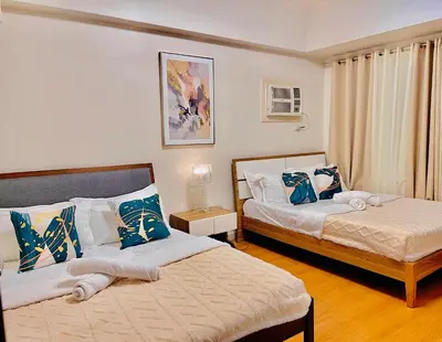 a bedroom with two beds with blue and white pillows at 1 Bedroom Condo near US Embassy and St Lukes Medical Clinic in Manila
