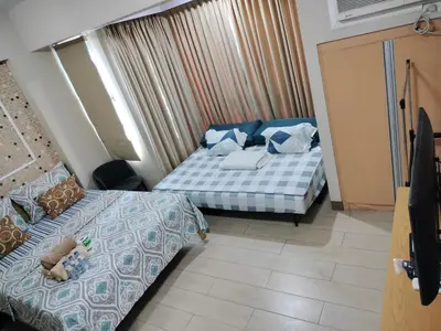 a hotel room with two beds and a tv at RQUI CONDOTEL in NAIA TERMINAL 3 at Two Palmtree Villas in Manila