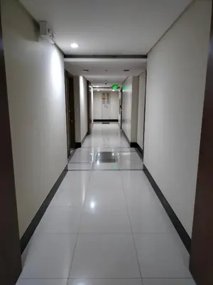 an empty corridor in an office building with white tiles at Room Across Naia Terminal 3 by Rqui in Manila