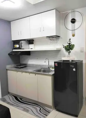 a kitchen with white cabinets and a black refrigerator at Chic 2BR Condo Unit at South Residences in Manila