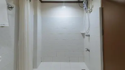 a bathroom with a shower with a shower curtain at Garden Plaza Hotel Manila in Manila