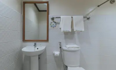a bathroom with a sink and a toilet and a mirror at Garden Plaza Hotel Manila in Manila