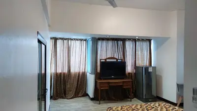a living room with a television and a room with curtains at MANILA BAY EXECUTIVE SUITE pearl of orient in Manila