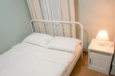 a bed with white pillows and a lamp on a table at Alea Residences in Manila