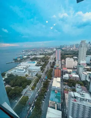 an aerial view of a city with buildings and water at Pearl Of The Orient Tower, in front of US Embassy in Manila