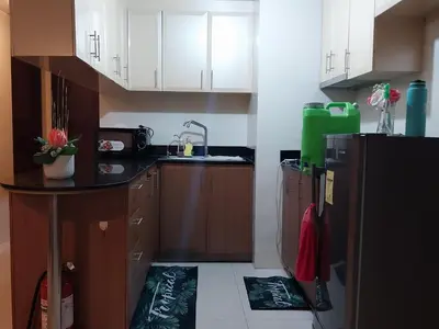 a kitchen with white cabinets and a black refrigerator at KENN PROPERTY in Manila