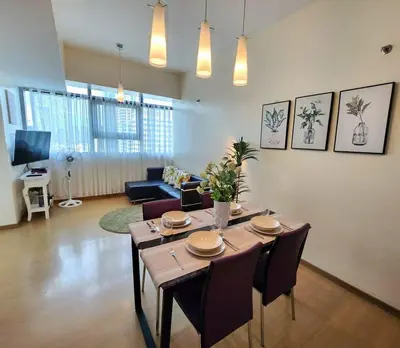 a living room with a wooden table and chairs at BGC Fresh & Cozy Studio near Burgos Circle with Fast Internet Connection in Manila