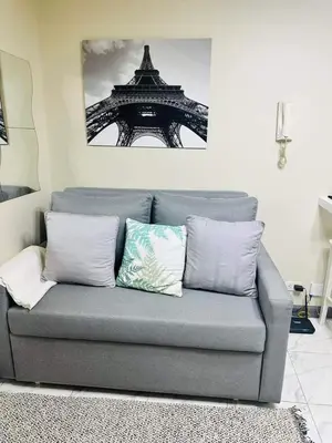 a gray couch with two pillows in a living room at Larue cozy room in Solemare Parksuites Paranaque in Manila