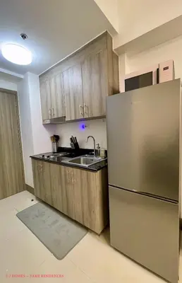a kitchen with wooden cabinets and a stainless steel refrigerator at EJ Homes - Fame Residences in Manila