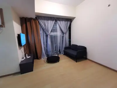 a living room with a black couch and a television at Caleze Properties AVANT at the Fort BGC Studio in Manila
