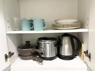 a kitchen shelf with pots and pans and plates at KL Tower Makati near AIM, Greenbelt 90mbps WIFI in Manila