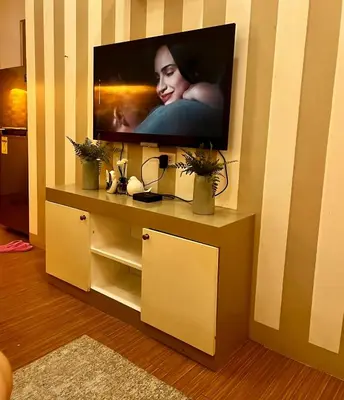 a flat screen tv sitting on top of a entertainment center at Comfy Condo near BGC, Makati and Naia in Manila