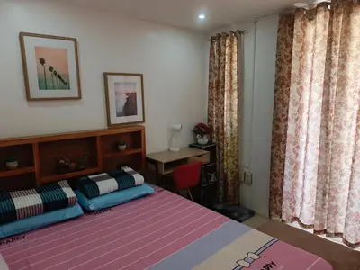 a bedroom with a bed and a desk and curtains at Misty Hills Guesthouse Amadeo - Tagaytay in Amadeo