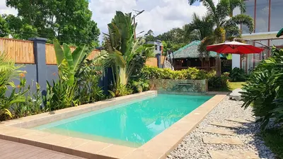 a swimming pool in a yard with an umbrella at The Farm Shack by SMS Hospitality in Amadeo