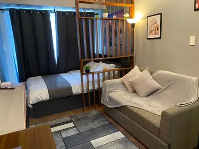 a living room with a couch and a bed at Cozy Crib @ Air Residences - Makati in Manila