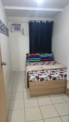 a small bedroom with a bed with a blue curtain at URBAN DECA O1257 Ortigas near SM EAST PASIG in Manila