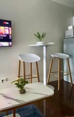 a room with two bar stools and a table with a plant at Scandinavian Studio in Makati in Manila