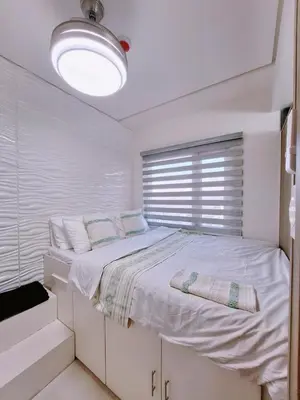 a white bedroom with a bed with a window at Coast Stay by J 40th floor Penthouse in Manila