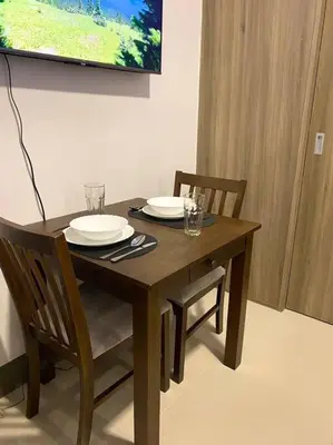a wooden table and chairs with plates and glasses on it at Modern 1-BR Condo Unit in Manila