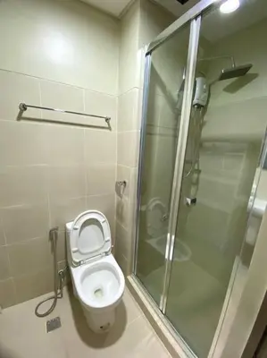 a bathroom with a toilet and a glass shower at Modern 1-BR Condo Unit in Manila